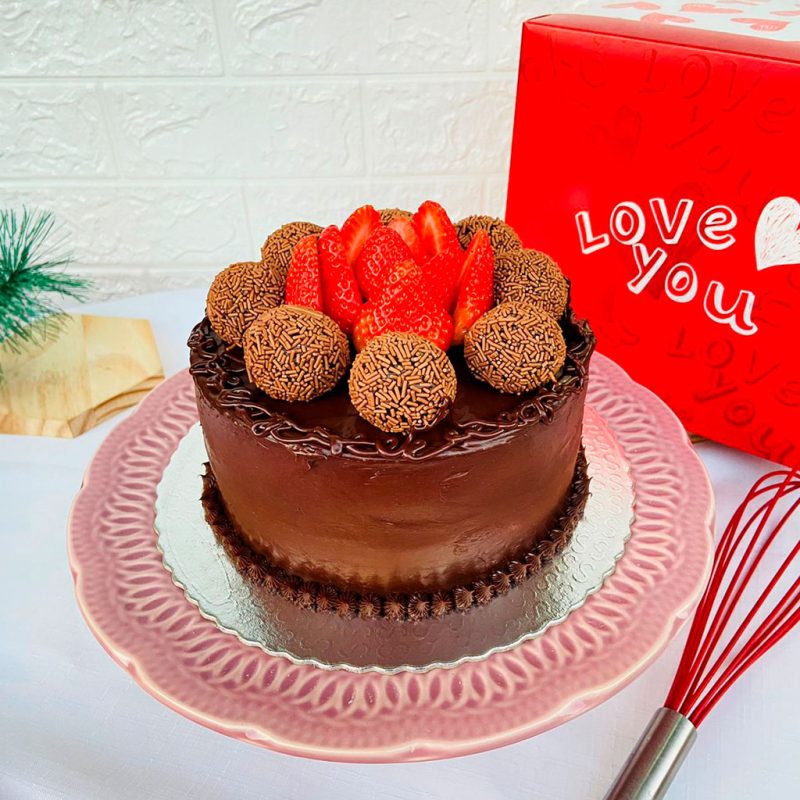 Bolo de chocolate com ganache de chocolate, brigadeiros e morangos no topo